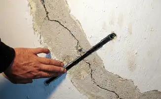 A wall with a large crack is being inspected by a professional in Norfolk, VA